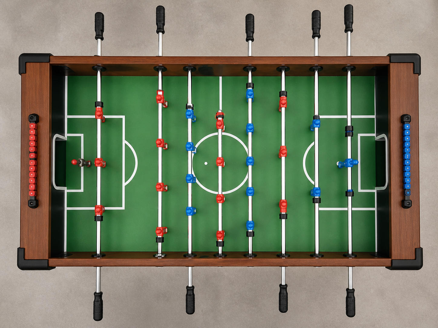 Vista cenital de un fulbito Roberto Sport — marco de madera, fieltro verde, jugadores rojos y azules